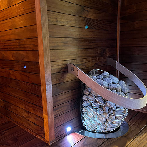 Sauna wall with Thermo-Radiata Pine wood paneling and stones